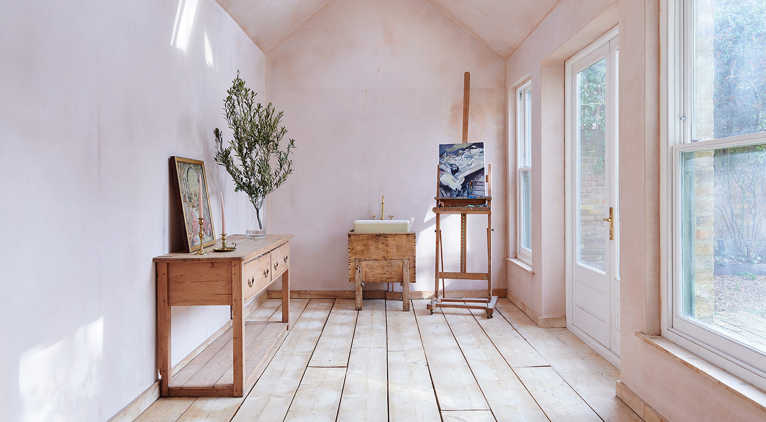 Artist studio with bare plaster walls, reclaimed wooden floorboards, pitched ceilings & skylights