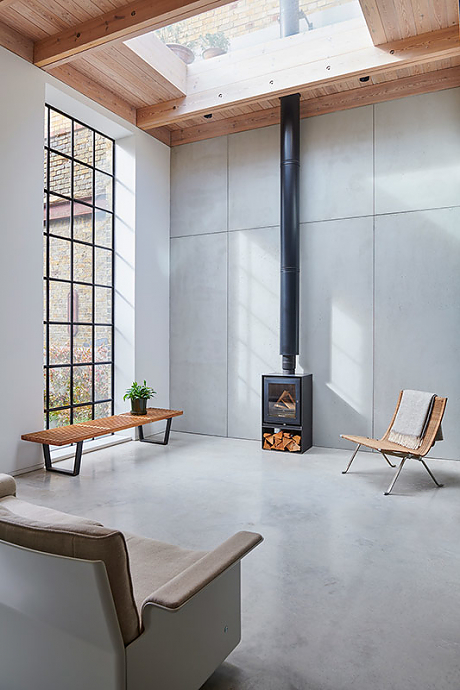Industrial open plan living space with crittle windows, concrete floor and wood burning stove