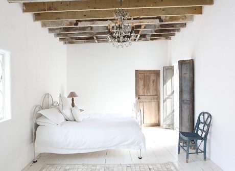 White, rustic bedroom with exposed beams and great natural light