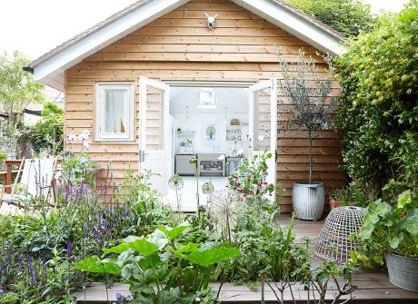 Stunning summerhouse with floorboards and doors that open to decked area in beautiful garden